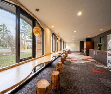 Long wooden bench and log stools facing garden windows at Hotel Daiheigen, Hokkaido