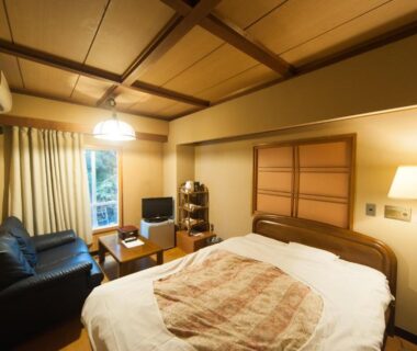 Cozy room with bed, sofa, low table and wood-beamed ceiling at Hotel Edoya Tokyo