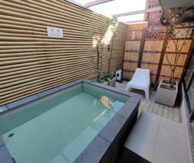 Enclosed outdoor tiled bath with bamboo screens and lounge chair at Hotel Edoya Tokyo