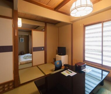 Traditional tatami room with low table, zabuton cushions and shoji screens, adjoining futon sleeping area at Hotel Edoya Tokyo