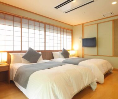 Three twin beds with shoji screens, wooden flooring and wall TV at Hotel Futaba in Niigata, Chūbu
