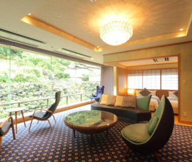 Lounge with low table, chairs and large window overlooking lush garden at Hotel Futaba in Niigata