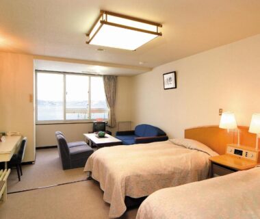 Twin beds with seating area and window at Hotel Grand Toya Hokkaidō