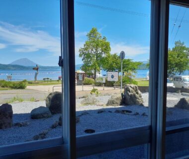 View through window to rock garden, Lake Toya, distant island and shoreline trees