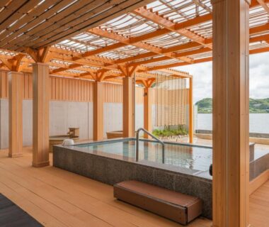 Covered wooden onsen with rectangular stone tub and lake view at Hotel Green Plaza Hamanako Shizuoka