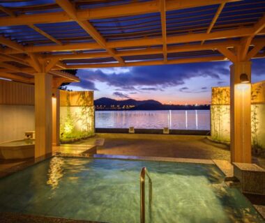 Covered lakeside onsen bath with wooden beams and evening lake view at Hotel Green Plaza Hamanako Shizuoka