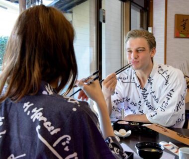 Two guests in yukata dining at a wooden table with bowls and chopsticks inside Hotel Hagoromo, Shizuoka