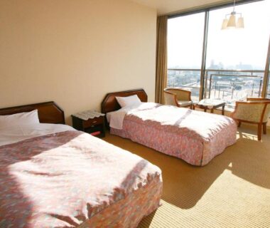 Twin beds, carpeted room with sliding glass door and city view at Hotel Hana Isawa, Yamanashi, Chūbu