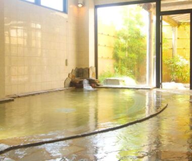 Tiled indoor onsen bath with stone fountain and glass doors to garden, Hotel Hana Isawa Yamanashi