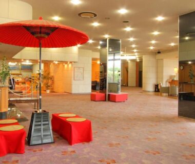 Spacious lobby with red umbrella and low benches at Hotel Hana Isawa in Yamanashi