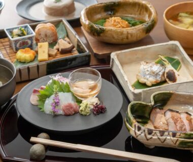 Assorted small Japanese dishes including sashimi, rice and soup on lacquered table at Hotel Hanakoyado Hyōgo