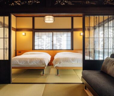 Tatami room with two beds, shoji screens, and a sofa at Hotel Hanakoyado in Hyōgo