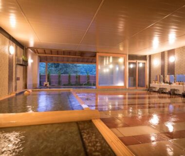Warm indoor baths with wooden edging and tiled floor at Hotel Hanamaki, Iwate
