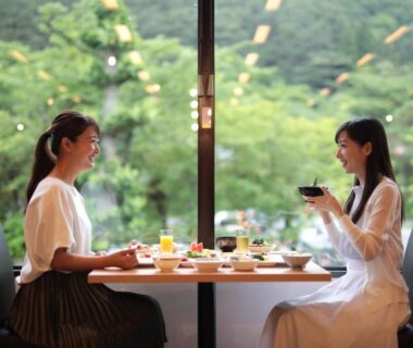 Two guests at a window table with cups and small dishes at Hotel Hanamaki in Iwate, Tohoku
