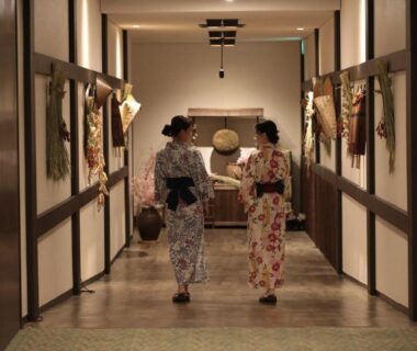 Two guests in yukata walking down a decorated ryokan corridor at Hotel Hanamaki in Iwate