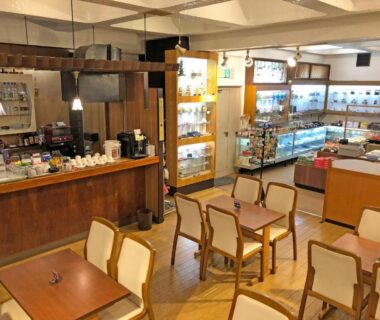 Cozy ryokan lobby cafe and gift shop with wooden tables and display cabinets at Hotel Harumoto in Tochigi