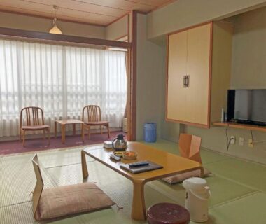 Tatami room with low table, floor chairs and window seating at Hotel Harumoto in Tochigi, Kantō, Japan
