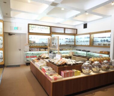 Interior view of Hotel Harumoto gift shop in Tochigi with glass cases and packaged souvenirs on wooden display tables