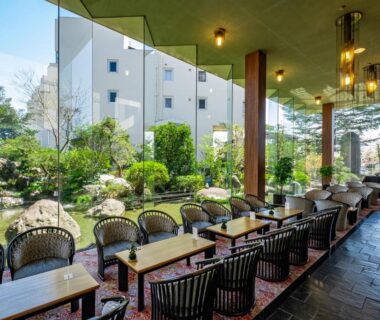 Covered terrace seating with wicker chairs and low tables overlooking Hotel Hatta garden in Yamanashi, Chūbu