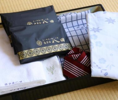 Folded yukata, slippers, and wrapped toiletries arranged on tatami mat as ryokan guest amenities