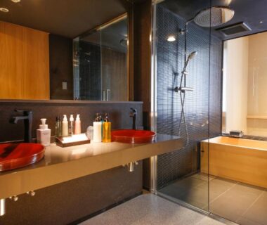 Glass shower and wooden soaking tub with red vessel sinks and toiletries, Hotel Honnoji, Kyoto