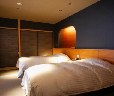 Twin beds with tatami flooring, wood headboard, shoji sliding doors and warm ambient lighting in a Kyoto ryokan room