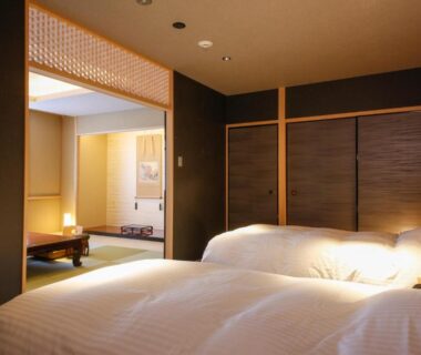 Bedroom with twin beds opening to tatami seating area and sliding wooden doors at Hotel Honnoji Kyoto