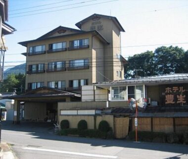 Multi-story ryokan exterior with entrance, street, and mountain backdrop, Hotel Housei, Nagano, Chubu