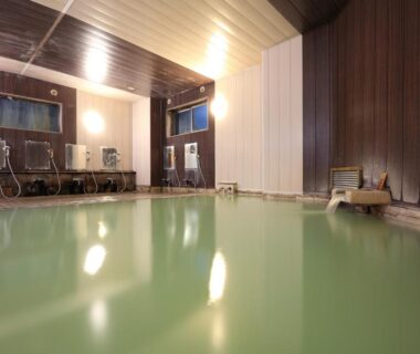 Milky green indoor onsen pool with wooden walls and stools at Hotel Ichibokaku, Nagano, Chūbu Japan