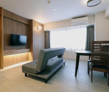 Bright modern guest room with sofa, TV and dining table at Hotel Ichibokaku in Nagano, Chūbu, Japan