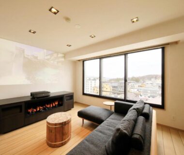 Comfortable lounge with sofa, fireplace, wooden floor and large window at Hotel Ichii in Gunma, Kantō