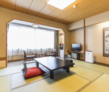 Traditional tatami room with low table, floor cushions and window seating at Hotel Ichii in Gunma