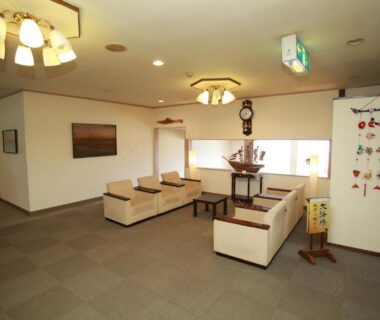 Spacious lobby with cream sofas, pendant lights and decorative wall hangings at Hotel Izumi in Hokkaidō