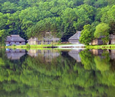 Wooden lakeside cottages reflected in calm water at Hotel Izumi in Hokkaidō