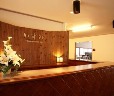 Reception with wooden counter and floral arrangement at Hotel Izumi in Hokkaidō