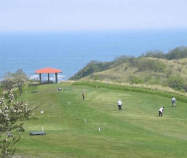Guests playing on grassy coastal lawn with pavilion at Hotel Izumi overlooking the sea in Hokkaidō, Japan