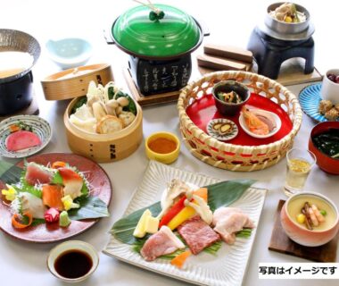 Assorted Japanese dishes with sashimi, steamed basket, soup bowls and condiments arranged on low dining table
