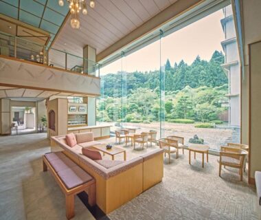 Open lounge with floor-to-ceiling window overlooking wooded hillside, seating area at Hotel Kameya, Miyagi, Tōhoku