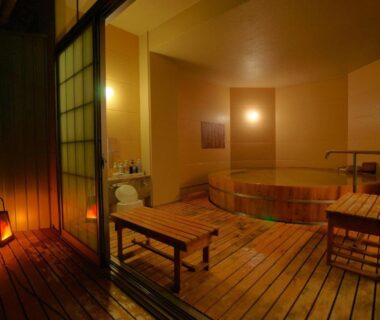 Warm wooden onsen bath room with bench, lantern lighting and sliding doors at Hotel Kaminoyu in Yamanashi