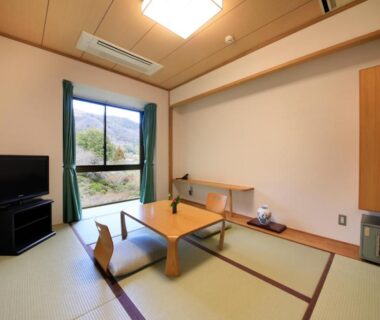 Tatami room with low table, floor chairs and mountain view at Hotel Kamogawaso, Hiroshima