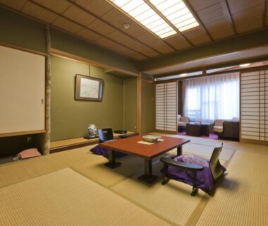 Tatami room with low table, floor chairs and shoji screens at Hotel Kan-ichi in Shizuoka