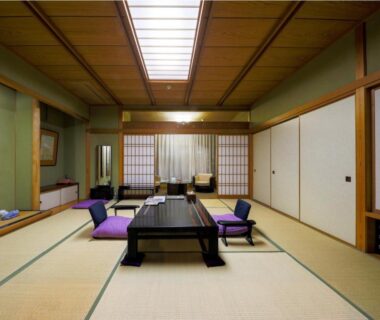 Spacious tatami room with low table, floor cushions and shoji screens at Hotel Kan-ichi, Shizuoka