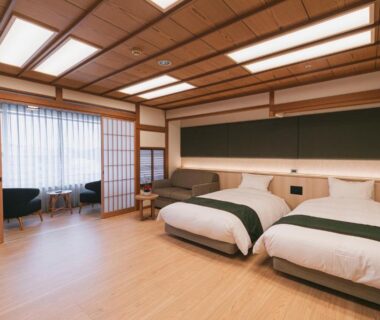 Tatami floor twin room with shoji screens, low beds and seating by the window at Hotel Kasuien, Saga