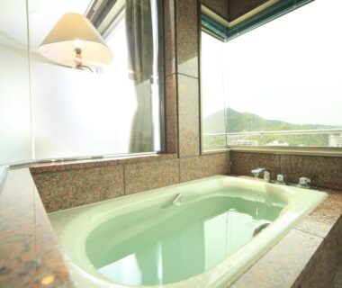 Stone soaking tub beside large corner window at Hotel Kasuien in Saga, Kyushu
