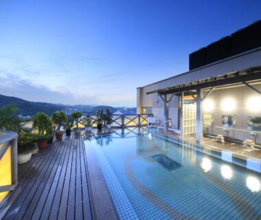 Outdoor rooftop pool with wooden deck and seating at Hotel Kasuien, Saga, Kyushu overlooking distant mountains
