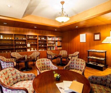 Warm wood-paneled lounge with bookshelves and round tables at Hotel Kazahaya in Ōita, Kyūshū, Japan