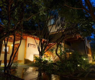 Night entrance pathway with trees and warm lantern lighting at Hotel Kazahaya in Ōita, Kyūshū, Japan
