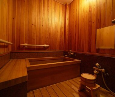 Cedar-lined bathing room with wooden tub, shower fittings and stool at Hotel Kazahaya, Oita, Kyushu