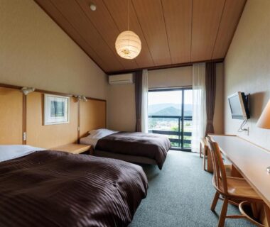 Twin beds, desk and balcony with mountain view at Hotel Kikori in Gifu Prefecture