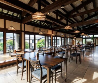 Wooden-beamed dining area with tables and large windows overlooking a garden at Hotel Kikori, Gifu